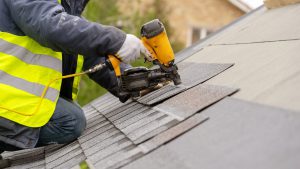 worker is drilling tiles on roof of a house