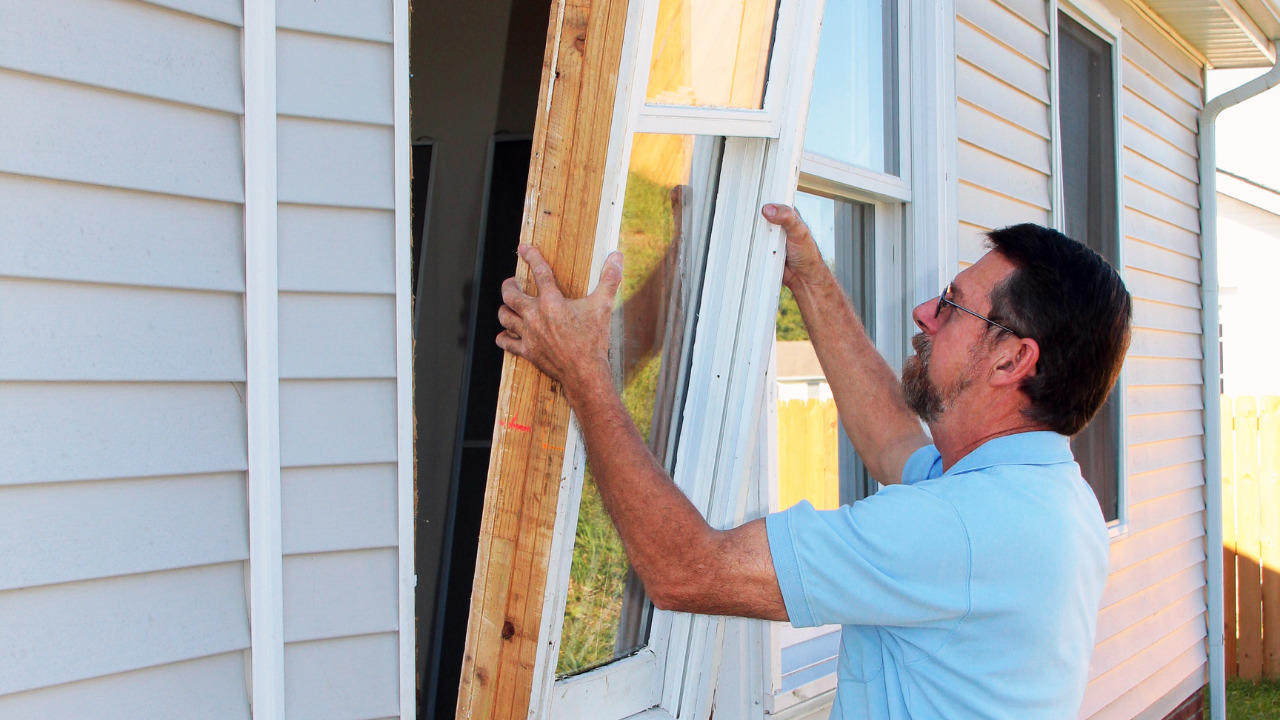 A man is replacing the damaged window of his house