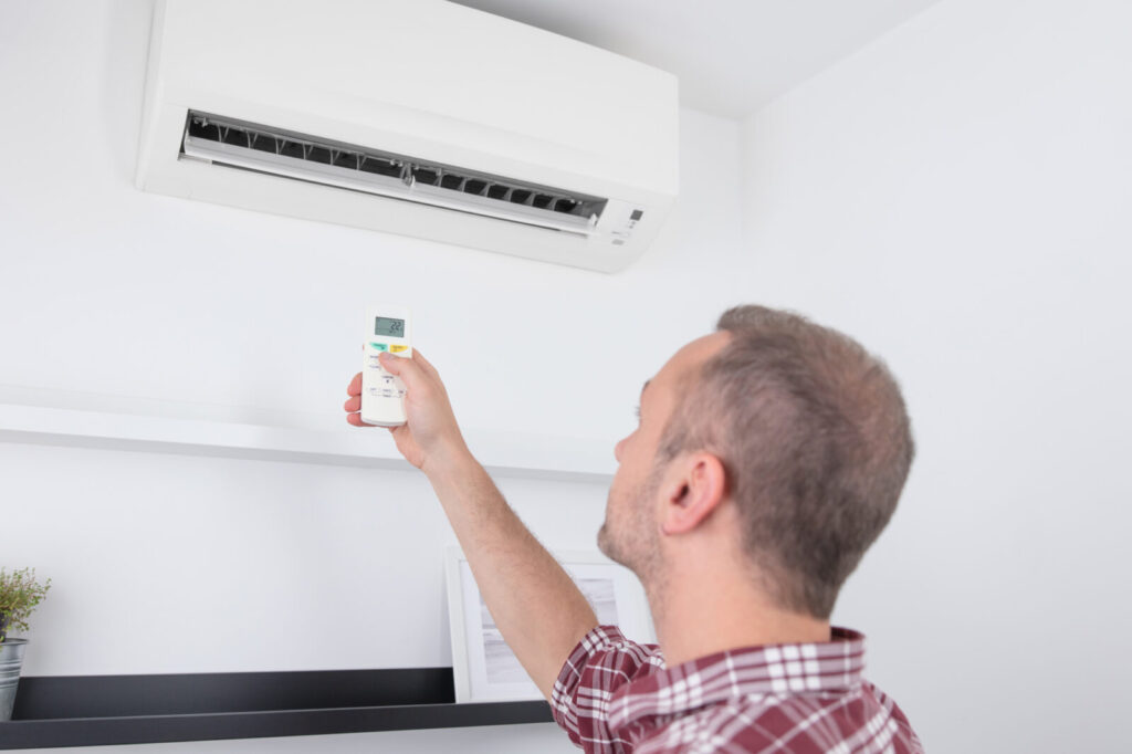 Man holding a modern AC unit remote.